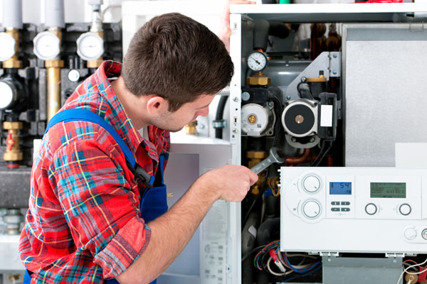 HVAC technician inspecting and repairing boiler controls in Thornton