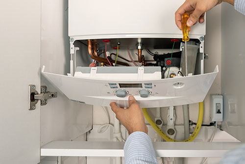 HVAC technician repairing an indoor boiler in Thornton